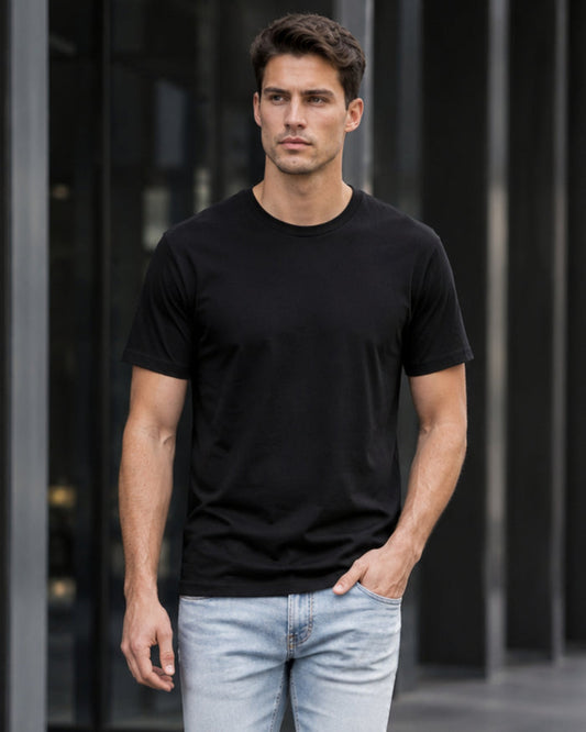 Man wearing a black t-shirt and light blue jeans against a dark background