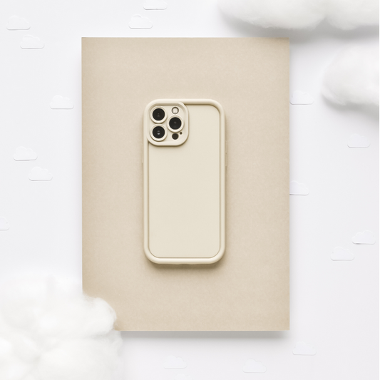 Pebble beige phone case with a soft finish on a tan notebook, surrounded by cotton and paper clouds.