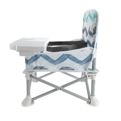 The Nuby Pop Up Booster Seat | Chevron is a foldable travel high chair with a tray, backrest, and sturdy legs with white feet. Featuring a white, blue, and gray zigzag pattern, it's perfect for feeding young children on the go.