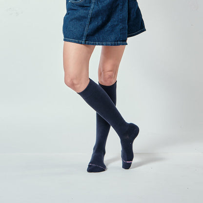 Knee-high compression socks in dark color worn with a denim skirt, showcasing the leg and sock design.