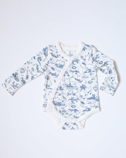 Blue-and-white toile bodysuit with flowers, bunnies, butterflies, hot air balloons, boats, moons, and suns.