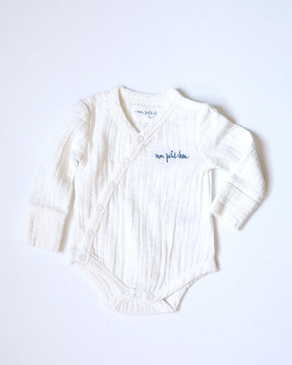 White muslin bodysuit with "mon petit chou" ("my little darling" in French) embroidered in blue on the chest.