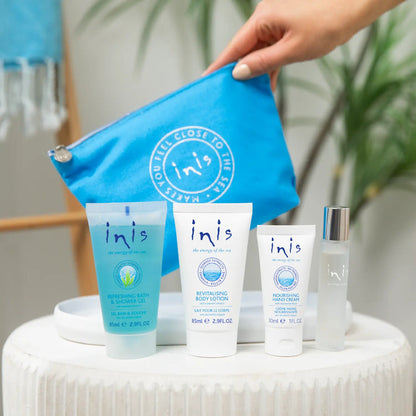 Inis skincare products including bottles and tubes on a white surface with a blue pouch.